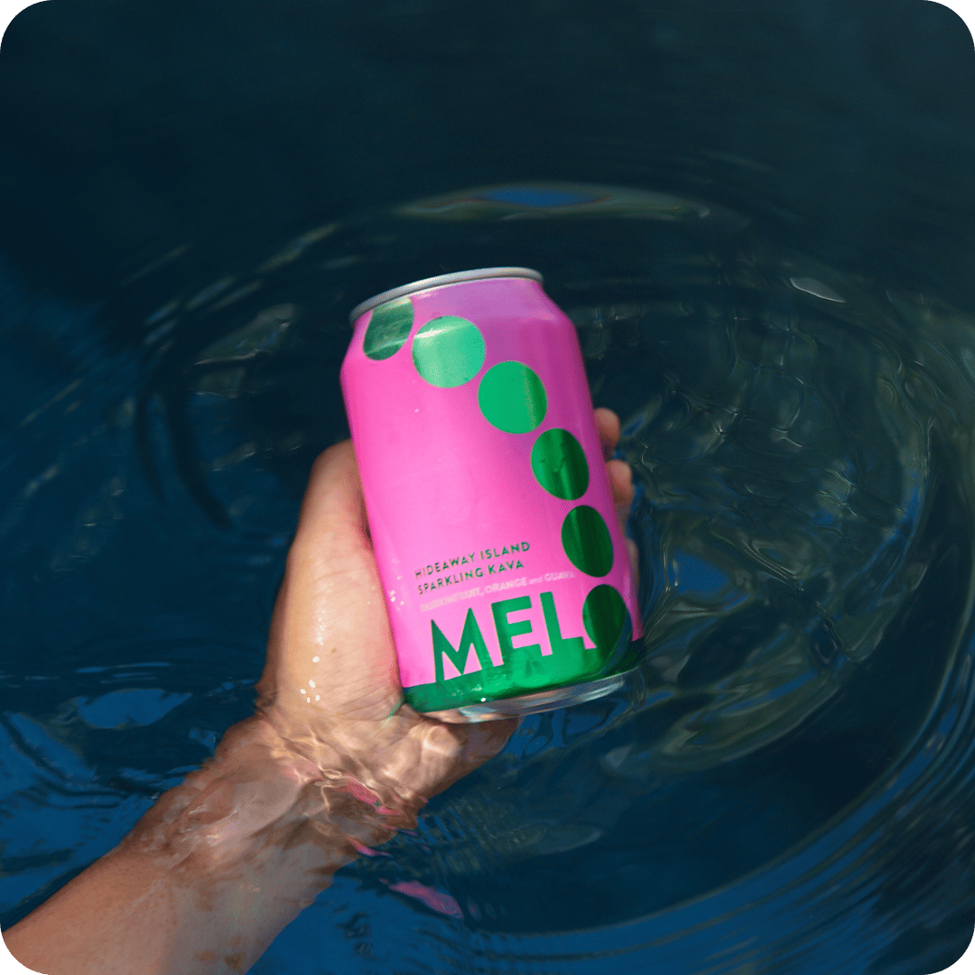 A hand holding a Melo Passionfruit, Orange & Guava sparkling kava can over a serene pool, highlighting the refreshing experience.