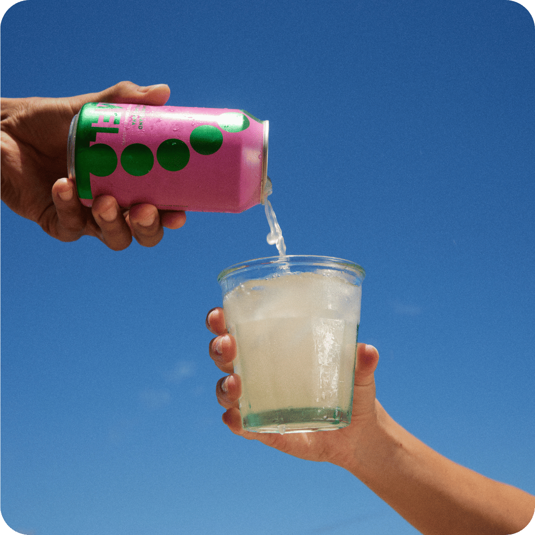 Pouring Melo kava into a glass under a bright blue sky, capturing the essence of summer refreshment