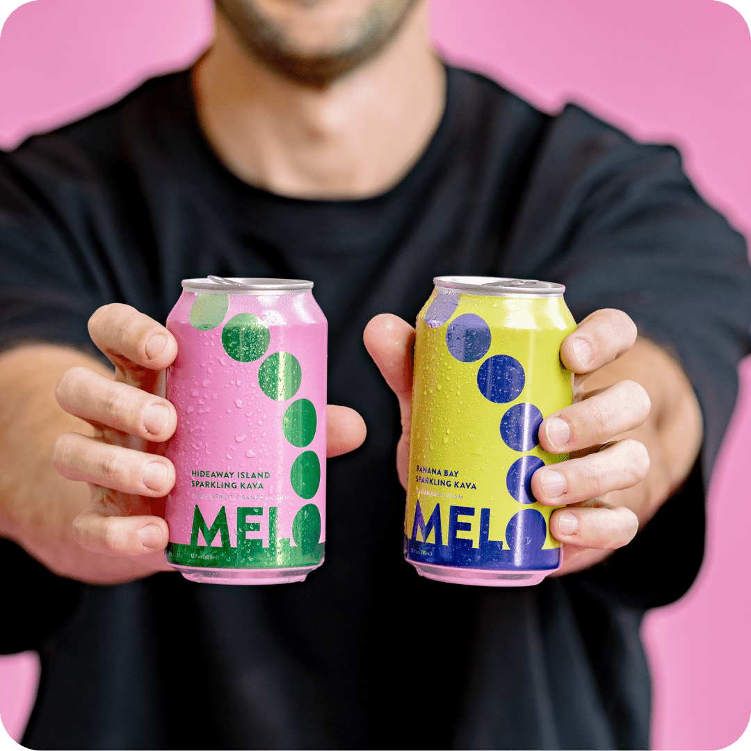 A person holds two Melo cans, Hideaway Island and Banana Bay. Highlights Melo’s vibrant branding and flavorful sparkling kava.